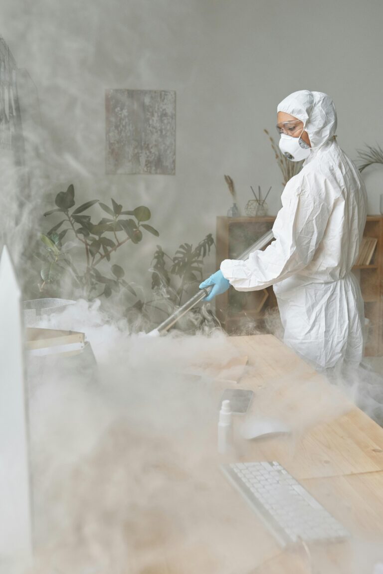 Professional in protective gear conducting odor removal in a smoke-affected indoor environment, emphasizing health and safety during remediation.